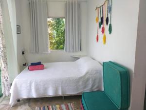 a bedroom with a bed and a green chair at Morada dos Elfos in Vale do Capao