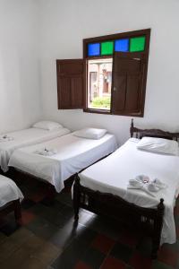 a group of three beds in a room with a window at Hotel Casa Antigua Buga in Buga