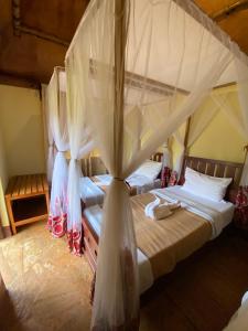 een slaapkamer met 2 bedden en een klamboe bij Patamu Restaurant & Lodge in Karatu