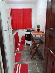 a small kitchen with a red curtain and a stove at Aconchego da Gil in Rio das Ostras