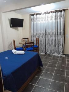 a bedroom with a blue bed and a table with chairs at Aconchego da Gil in Rio das Ostras