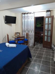 リオ・ダス・オストラスにあるAconchego da Gilのベッドルーム(青いベッド1台、テーブル、椅子付)