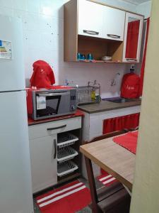 a small kitchen with a table and a microwave at Aconchego da Gil in Rio das Ostras