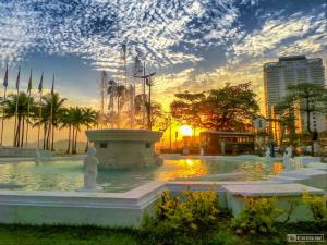 una fuente en un parque con la puesta de sol en el fondo en Apartamento em Santos no Gonzaga em frente a praia en Santos