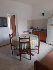 a kitchen with a table and two chairs and a refrigerator at Ruka Leufu in Santa Rosa de Calamuchita