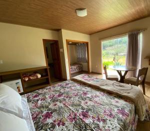 a bedroom with a bed and a table and a window at Pousada Rural Recanto do Lago in Pedra Azul