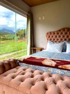 a bedroom with a bed and a large window at Pousada Rural Recanto do Lago in Pedra Azul