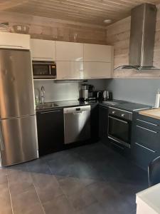 una cocina con electrodomésticos de acero inoxidable y armarios negros en Villa Sappee, en Sappee