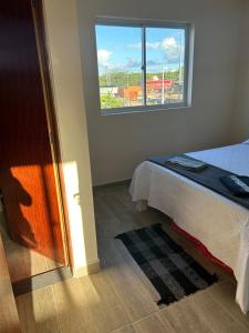 um quarto com uma cama e uma janela em Agapanto Praia em Marechal Deodoro