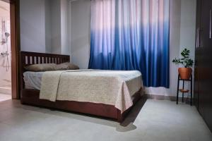 a bedroom with a bed with a blue curtain at The Pearls in East Legon