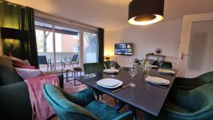 a dining room with a table and green chairs at ARCHIPEL - Balkon - nahe Hamburg - Lounge - Smart TV - Parking in Geesthacht