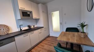 a kitchen with white cabinets and a wooden table at Archipel Homes neu & modern, zentral, nähe Hamburg und Lüneburg in Geesthacht