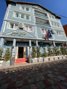 a blue building with a flag in front of it at Hotel Heimli in Prishtinë