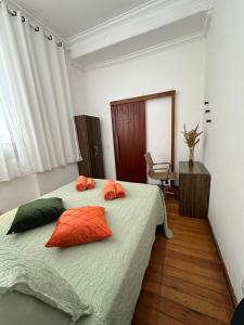 7 persons - 140 m2 - Sambódromo - LAPA - House - Casa - Netflix في ريو دي جانيرو: غرفة نوم مع سرير مع وسائد برتقالية وأخضر