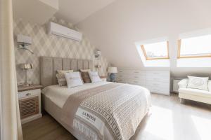 a white bedroom with a bed and a chair at WINNINGS APARTAMENTY NAD MORZEM RIVIERA BLUE in Ustronie Morskie