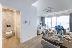 a dining room and living room with a table and chairs at WINNINGS APARTAMENTY NAD MORZEM RIVIERA BLUE in Ustronie Morskie +26 photos