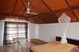 a bedroom with a ceiling fan and a bed and a table at Villa Mandel Nafio, Haus mit Garten nahe dem Atlantik in Ouoran