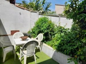 einen Tisch und Stühle auf einer Terrasse mit Gras in der Unterkunft Toulousaine avec jardin proche centre wifi in Toulouse