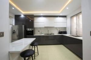 a kitchen with white cabinets and black counters and stools at Unit i2 City House (Sleeps 6) in Lagos