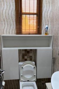 a white toilet in a bathroom with a window at Unit i2 City House (Sleeps 6) in Lagos