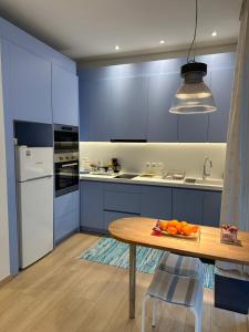 a kitchen with blue cabinets and a table with a plate of oranges at Athens Sea Front Apartment - Athenian Riviera in Varkiza