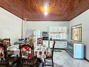 eine Küche mit einem Tisch und Stühlen sowie eine Küche mit weißen Geräten in der Unterkunft Linda Edícula com Churrasqueira em casa de Familia in Foz do Iguaçu