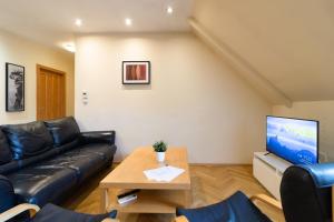 uma sala de estar com um sofá de couro preto e uma mesa em Prague Duplex 2BR Apart w. AC in New Town em Praga