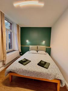 Schlafzimmer mit einem großen Bett mit einem grünen Kopfteil in der Unterkunft Le Charme des Remparts Boulonnais in Boulogne-sur-Mer