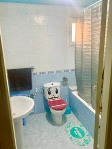 a bathroom with a toilet with a face drawn on it at Dream Appartement El Aouina in Tunis