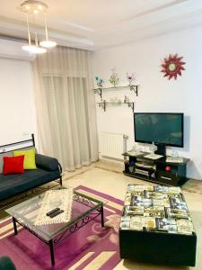 uma sala de estar com um sofá e uma televisão em Dream Appartement El Aouina em Tunes