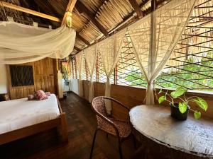 a bedroom with a bed and a table and a window at Bella Flor Hostel Palomino in Palomino