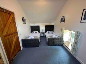 een kleine kamer met 2 bedden en een deur bij The Coach House North Wales, Amazing views , hot tub, log fire in Halkyn