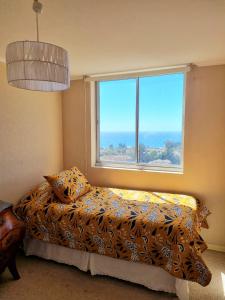 ein Schlafzimmer mit einem Bett und einem großen Fenster in der Unterkunft Departamento Laguna Vista in Algarrobo