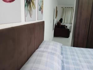 a bed in a bedroom with a person sitting on a couch at Apartamento Completo A25 Flat Centro in Mogi das Cruzes