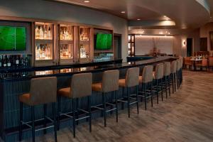 a bar with a row of chairs and televisions at Chicago Marriott Southwest at Burr Ridge in Burr Ridge