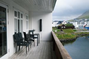 a porch with chairs and a table and water at Spacious City Center Home by the Sea in Klaksvík