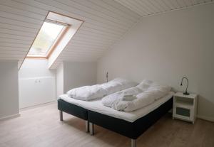 a bedroom with a bed with white sheets and a window at Spacious City Center Home by the Sea in Klaksvík