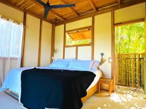 ein Schlafzimmer mit einem Bett in einem Zimmer mit einem Fenster in der Unterkunft Calamocha Lodge in Playa Santa Teresa