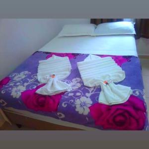 Una cama con ropa blanca y rosas. en Pousada Caribe Brasileiro, en Maragogi