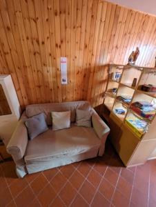 a couch in a room with a wooden wall at Le Marmotte - Appartamento in Abetone