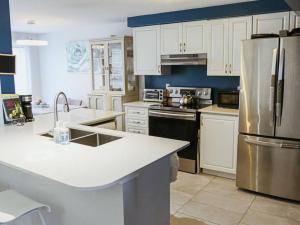 a kitchen with white cabinets and a stainless steel refrigerator at Kitchener-Waterloo Cozy House in Kitchener
