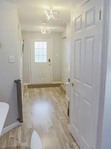 een lege kamer met een witte deur en houten vloeren bij Kitchener-Waterloo Cozy House in Kitchener