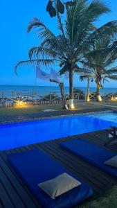 a swimming pool with palm trees and the ocean at night at Vila Sereia Caraiva in Caraíva