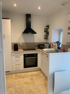 a kitchen with white cabinets and a stove top oven at La petite Bretonne in Plounérin
