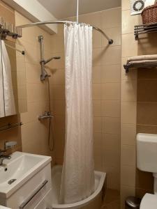 a bathroom with a white shower curtain and a sink at cream apartment in Banja Luka