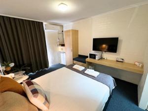 um quarto de hotel com uma cama grande e uma televisão em Econo Lodge Gateway Tamworth em Tamworth
