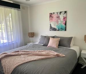 a bedroom with a large bed with pink and gray pillows at Homburg Haven in Tanunda