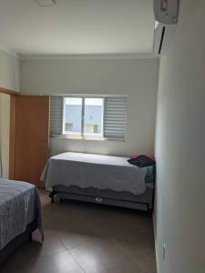 a bedroom with two beds and a window at Aconchegante casa na represa. in Itaí