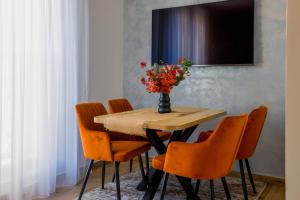 einen Esstisch mit orangefarbenen Stühlen und eine Vase mit Blumen in der Unterkunft Apartmani Aria Jahorina in Jahorina