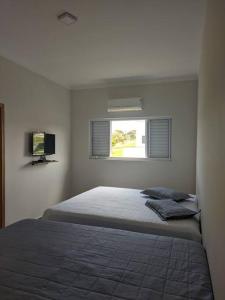 um quarto com uma cama e uma janela em Aconchegante casa na represa. em Itaí